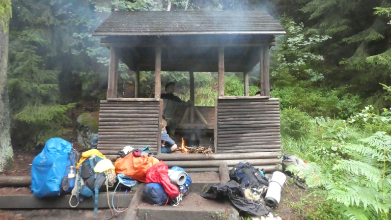 Schutzhütte mit Rucksäcken dvor, in der Pfadfinder kochen.